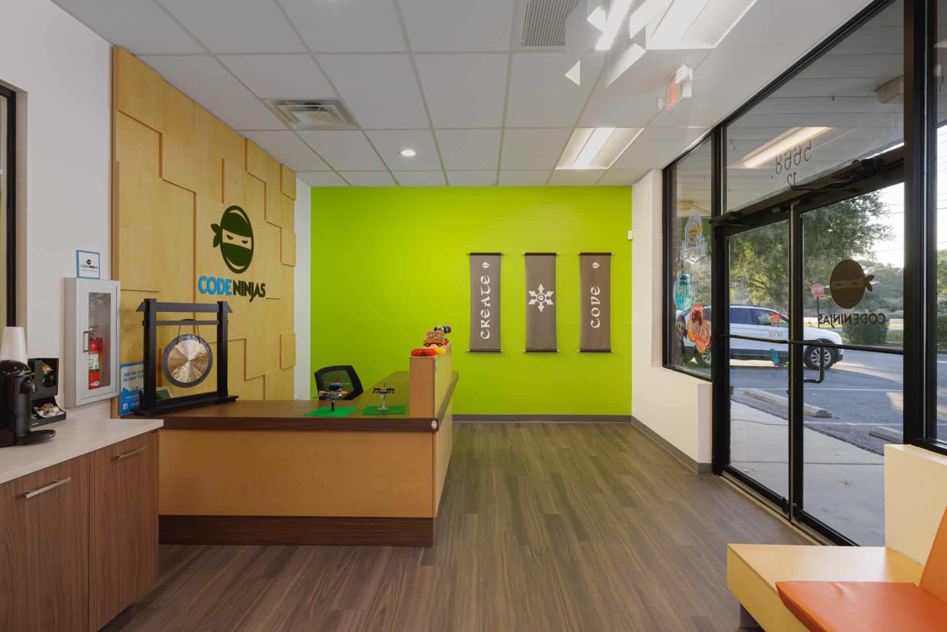 The vibrant lobby view highlights the lime green accent wall that serves as a high-energy backdrop for branded banners and the reception desk.