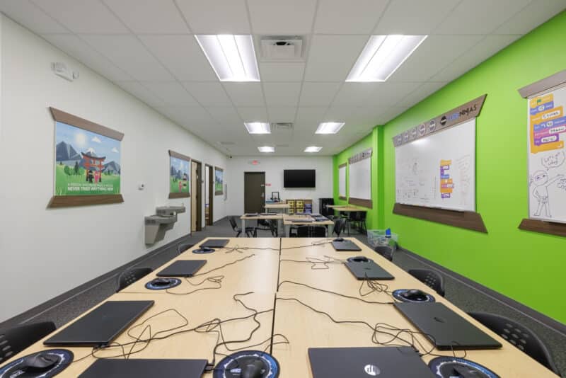 Code Ninjas reception area with wooden feature wall, lime green accents, and a light wood desk.