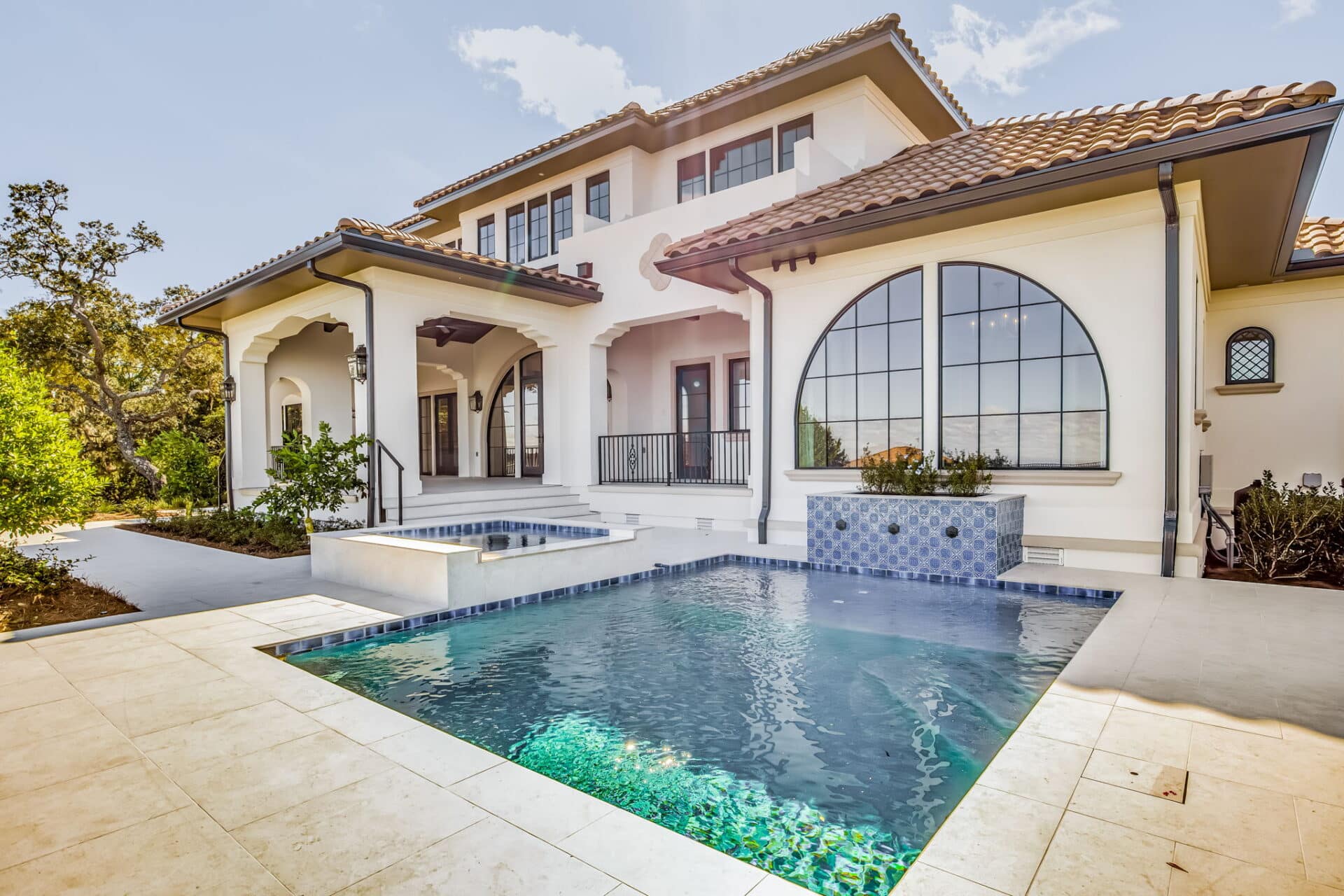 Architectural details and the swimming pool deck, showing the blend of white stucco, terracotta tile roofing, and black window trim.