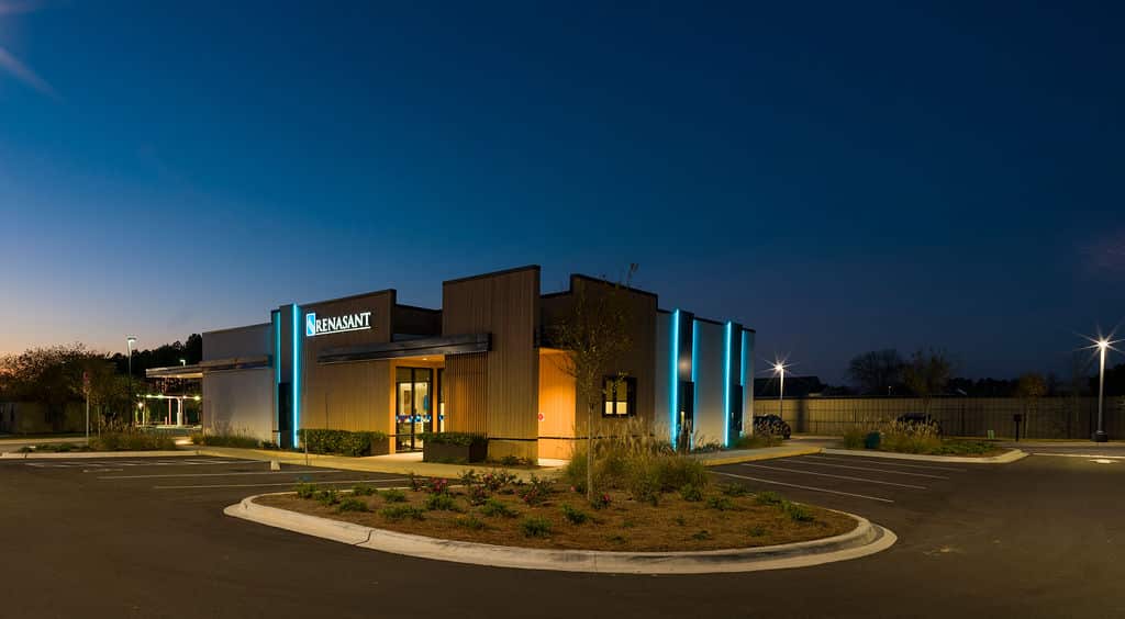 Nighttime view of the bank building illuminated with vertical cyan LED light strips.
