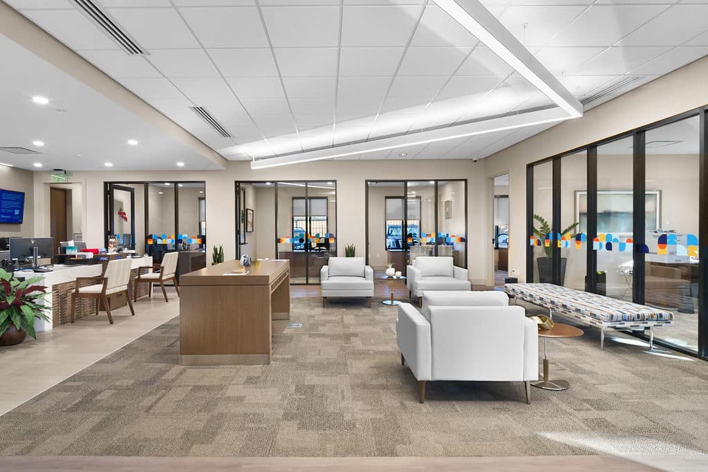 Lobby view showing glass-walled private offices with branded colorful decals and modern furniture.
