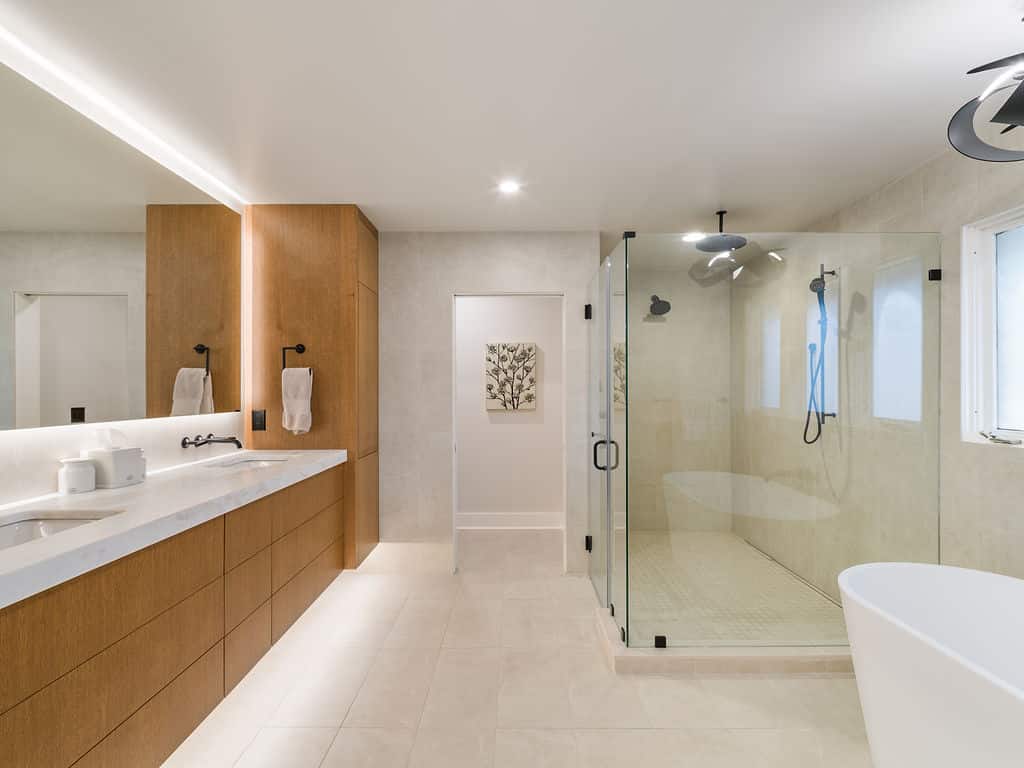 Large master bathroom with a floating double oak vanity, a glass-enclosed walk-in shower, and a freestanding soaking tub.